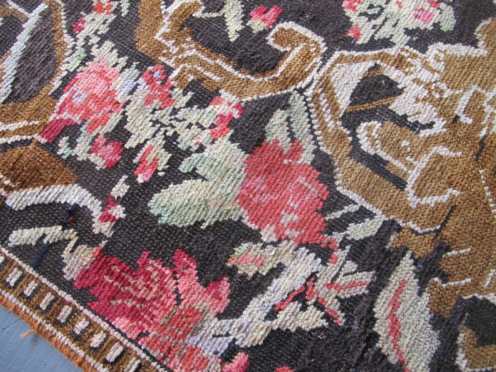 A long antique hand-knotted wool runner featuring red floral motifs and scrolling foliage against a dark brown background. View IX