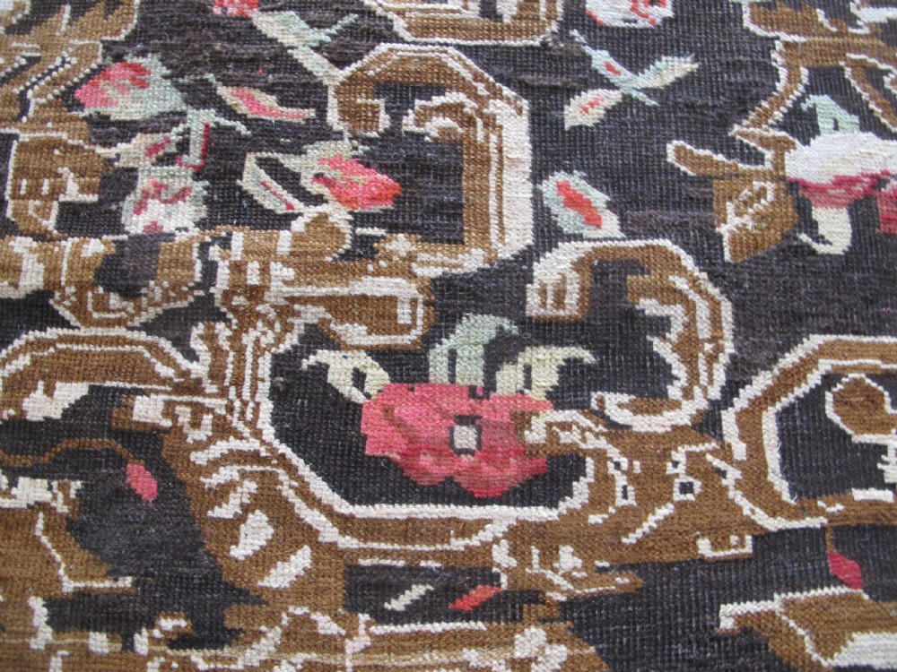 A long antique hand-knotted wool runner featuring red floral motifs and scrolling foliage against a dark brown background. View X