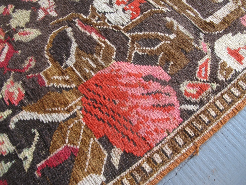 A long antique hand-knotted wool runner featuring red floral motifs and scrolling foliage against a dark brown background. View XI