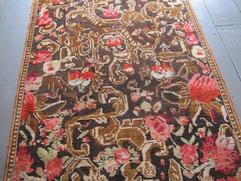 A long antique hand-knotted wool runner featuring red floral motifs and scrolling foliage against a dark brown background. View XII