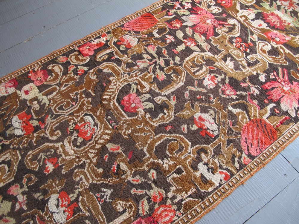 A long antique hand-knotted wool runner featuring red floral motifs and scrolling foliage against a dark brown background. View XIII