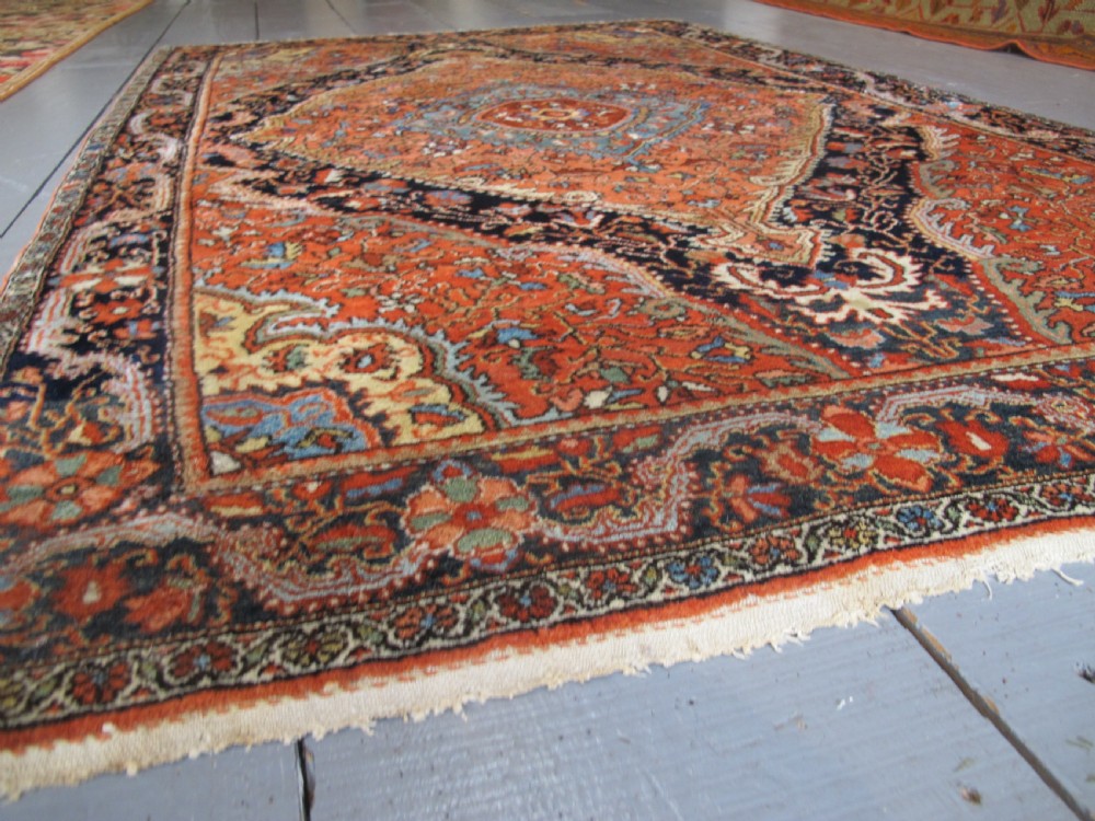 An antique Persian Jozan rug featuring a terracotta red field, central diamond medallion, dark navy spandrels, and intricate floral motifs. View III