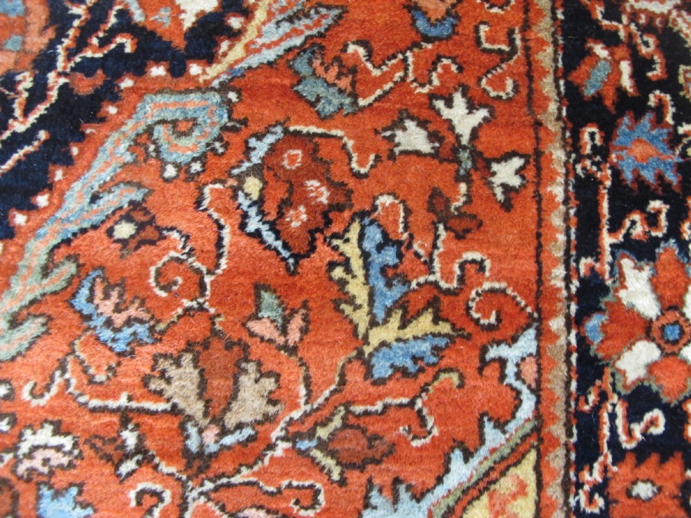 An antique Persian Jozan rug featuring a terracotta red field, central diamond medallion, dark navy spandrels, and intricate floral motifs. View IV