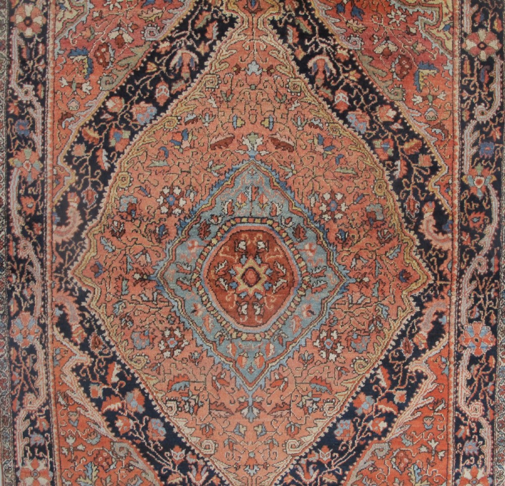 An antique Persian Jozan rug featuring a terracotta red field, central diamond medallion, dark navy spandrels, and intricate floral motifs. View V