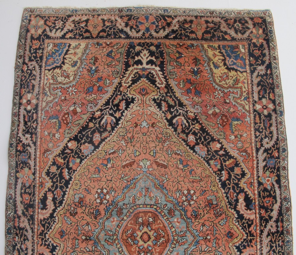 An antique Persian Jozan rug featuring a terracotta red field, central diamond medallion, dark navy spandrels, and intricate floral motifs. View VI