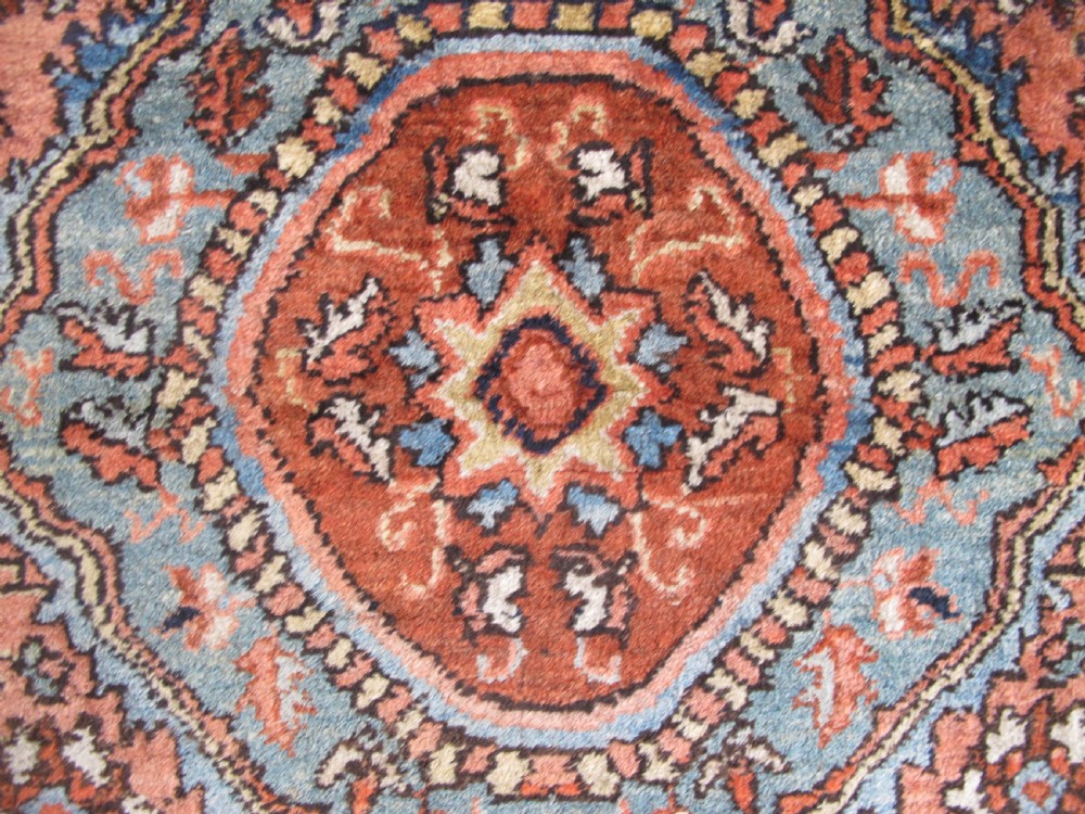 An antique Persian Jozan rug featuring a terracotta red field, central diamond medallion, dark navy spandrels, and intricate floral motifs. View VIII