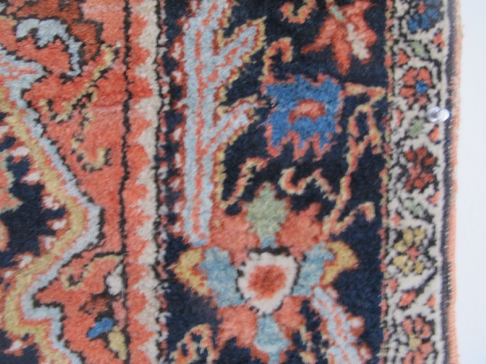 An antique Persian Jozan rug featuring a terracotta red field, central diamond medallion, dark navy spandrels, and intricate floral motifs. View IX