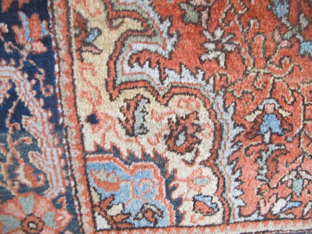 An antique Persian Jozan rug featuring a terracotta red field, central diamond medallion, dark navy spandrels, and intricate floral motifs. View X