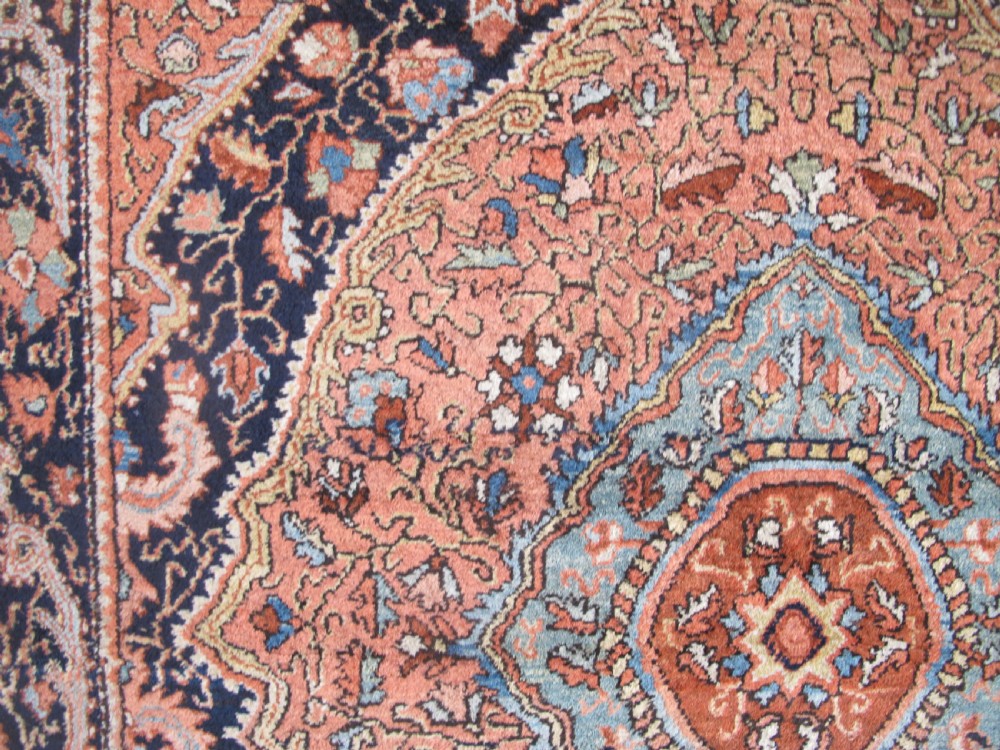 An antique Persian Jozan rug featuring a terracotta red field, central diamond medallion, dark navy spandrels, and intricate floral motifs. View XI