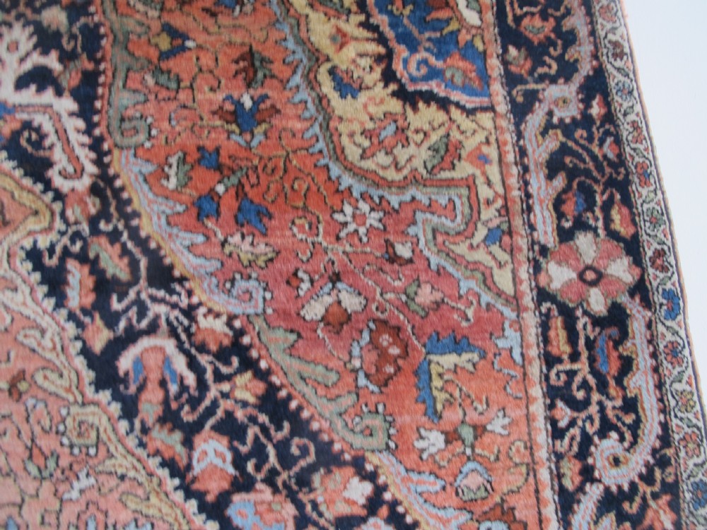 An antique Persian Jozan rug featuring a terracotta red field, central diamond medallion, dark navy spandrels, and intricate floral motifs. View XII