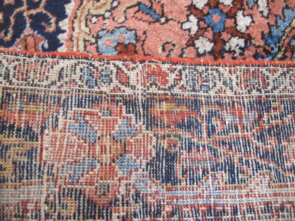 An antique Persian Jozan rug featuring a terracotta red field, central diamond medallion, dark navy spandrels, and intricate floral motifs. View XIII