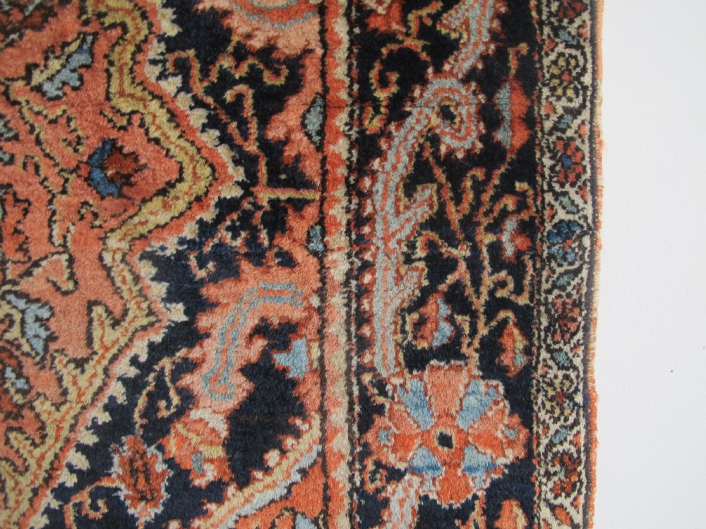An antique Persian Jozan rug featuring a terracotta red field, central diamond medallion, dark navy spandrels, and intricate floral motifs. View XIV