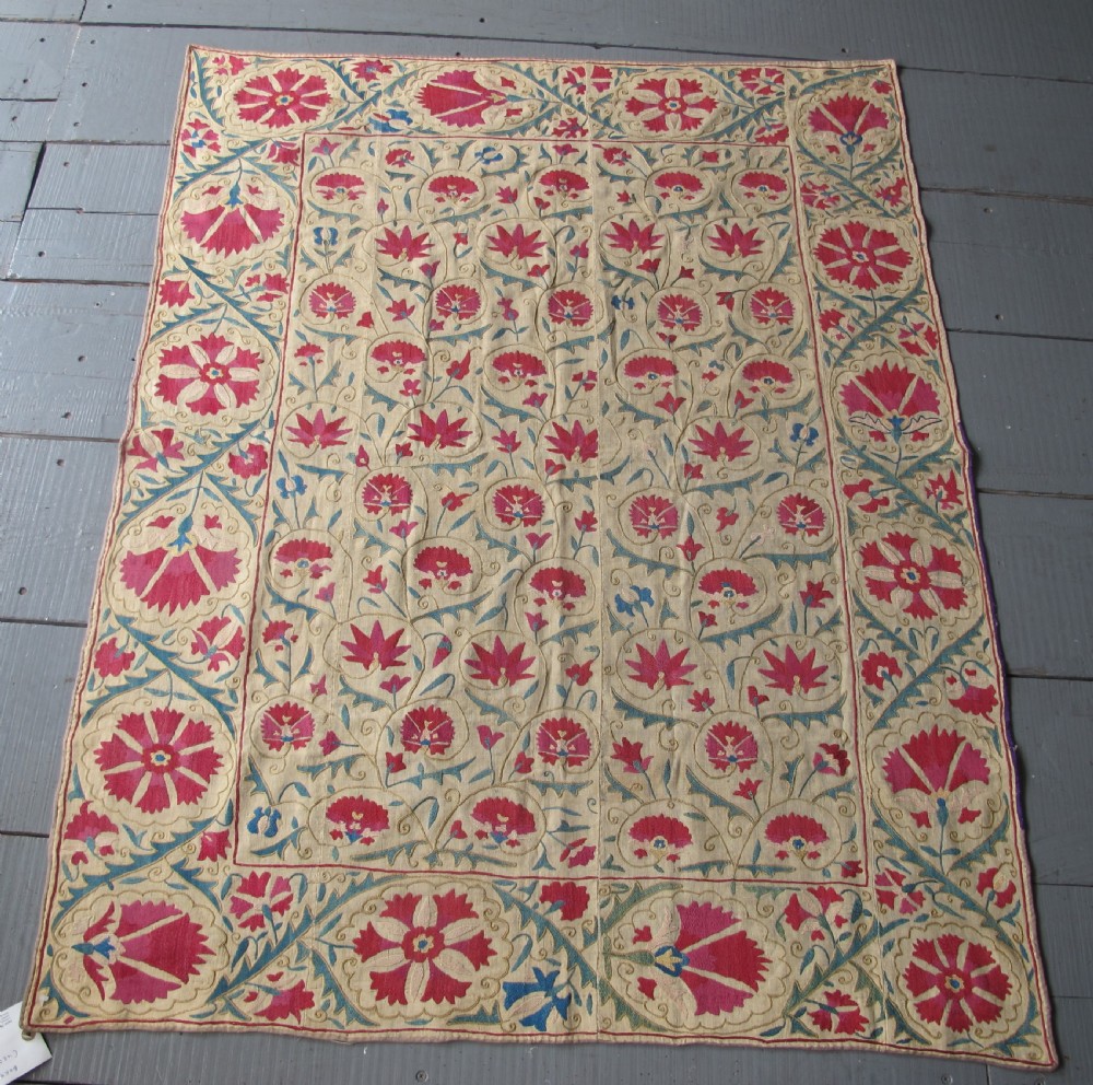 A rectangular antique silk-embroidered Suzani textile featuring crimson floral motifs and scrolling leaf borders on a beige cotton ground. View XVII