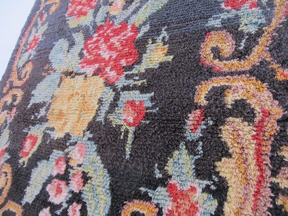 An early 20th-century Scandinavian Rya wool rug featuring a central floral bouquet in yellow, red, and green with scrollwork borders on a black field. View VII