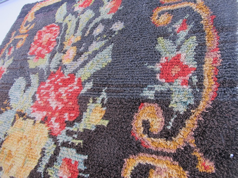 An early 20th-century Scandinavian Rya wool rug featuring a central floral bouquet in yellow, red, and green with scrollwork borders on a black field. View VIII