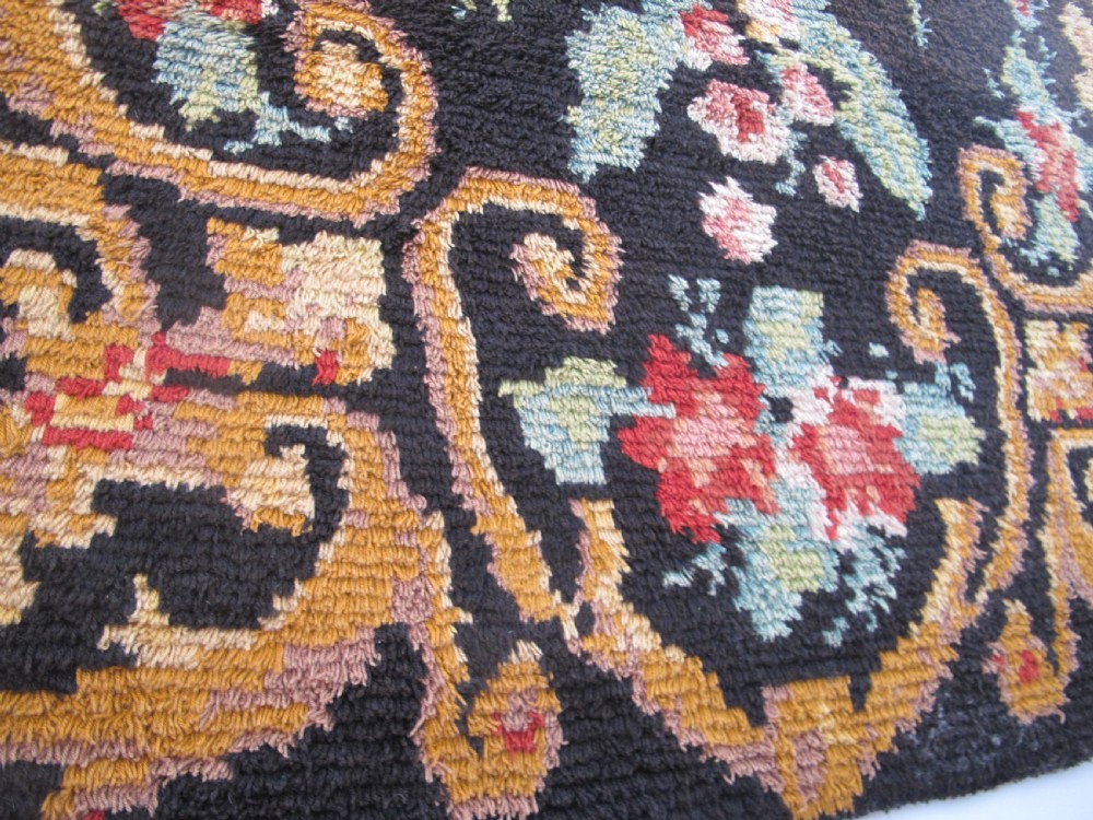 An early 20th-century Scandinavian Rya wool rug featuring a central floral bouquet in yellow, red, and green with scrollwork borders on a black field. View XI