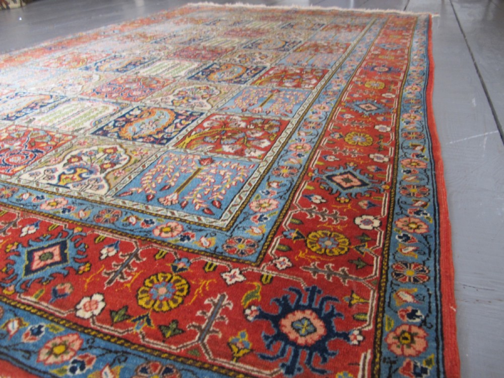 A rectangular hand-knotted Persian Qum rug featuring a central field of grid compartments filled with botanical and cypress motifs framed by a red border. View III