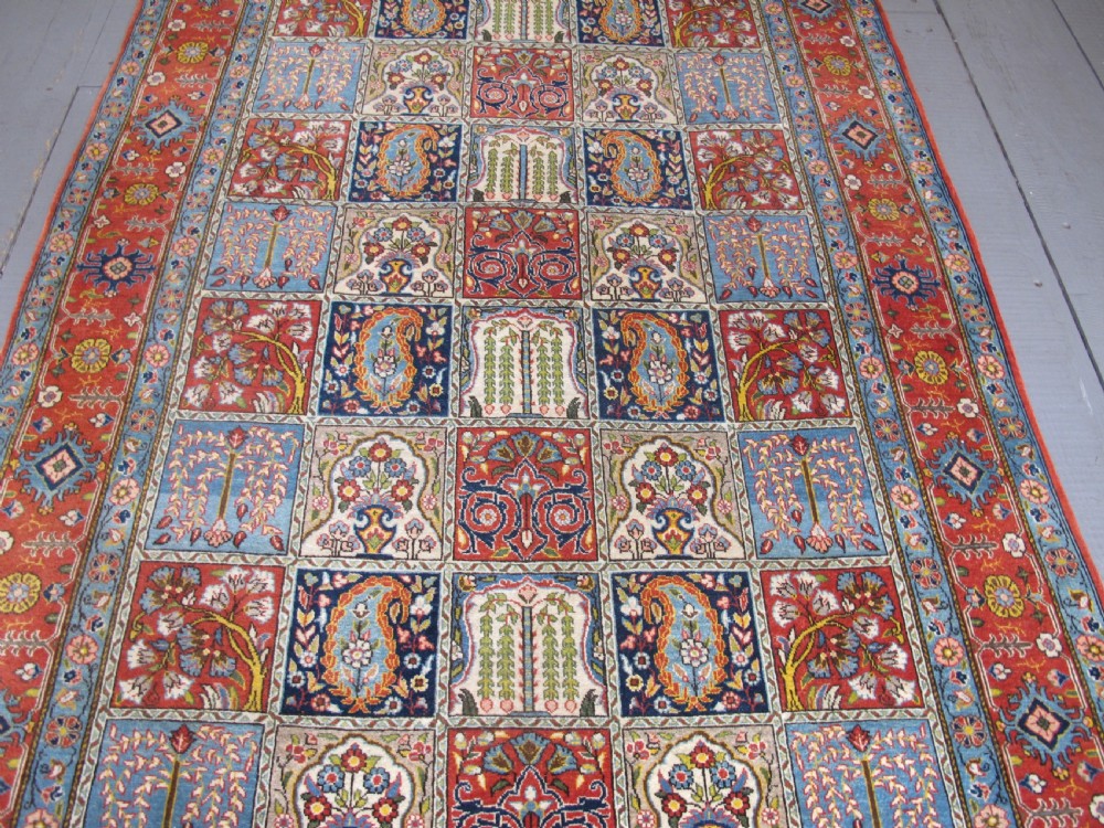 A rectangular hand-knotted Persian Qum rug featuring a central field of grid compartments filled with botanical and cypress motifs framed by a red border. View VI