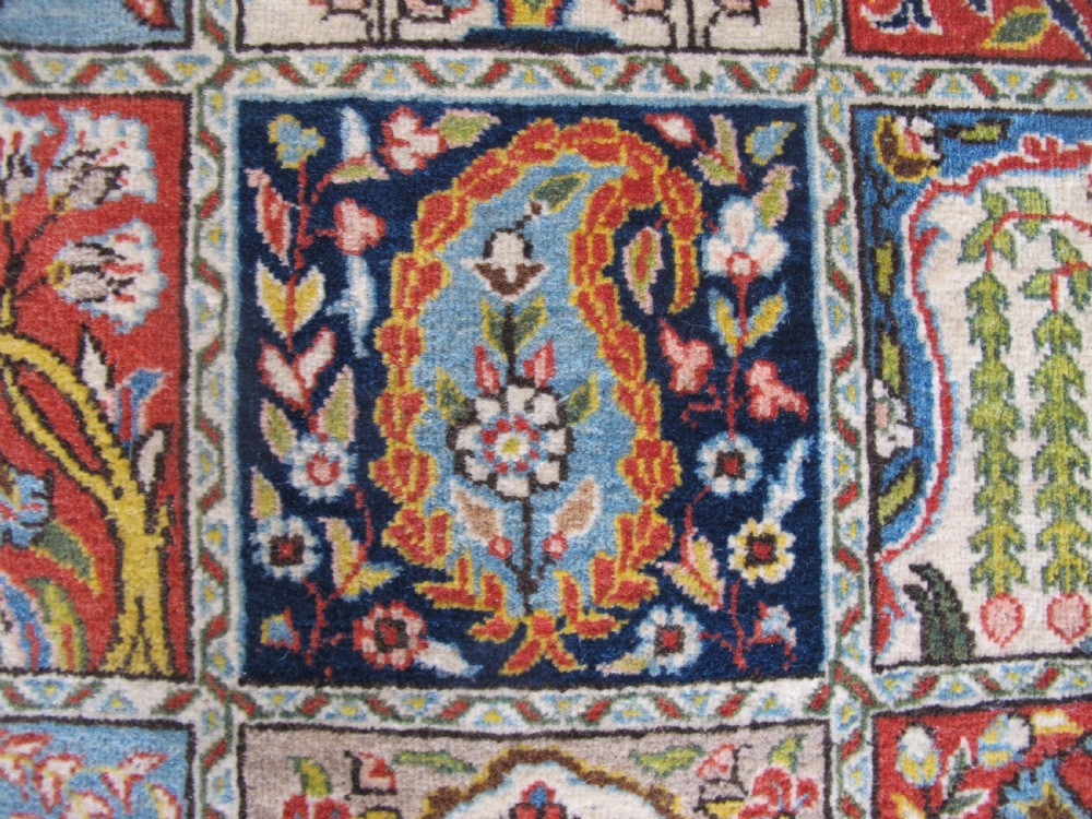 A rectangular hand-knotted Persian Qum rug featuring a central field of grid compartments filled with botanical and cypress motifs framed by a red border. View IX