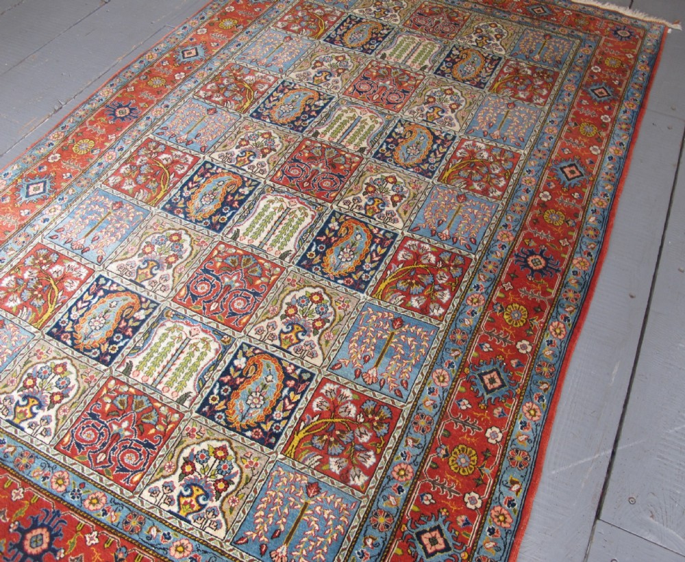 A rectangular hand-knotted Persian Qum rug featuring a central field of grid compartments filled with botanical and cypress motifs framed by a red border. View XI