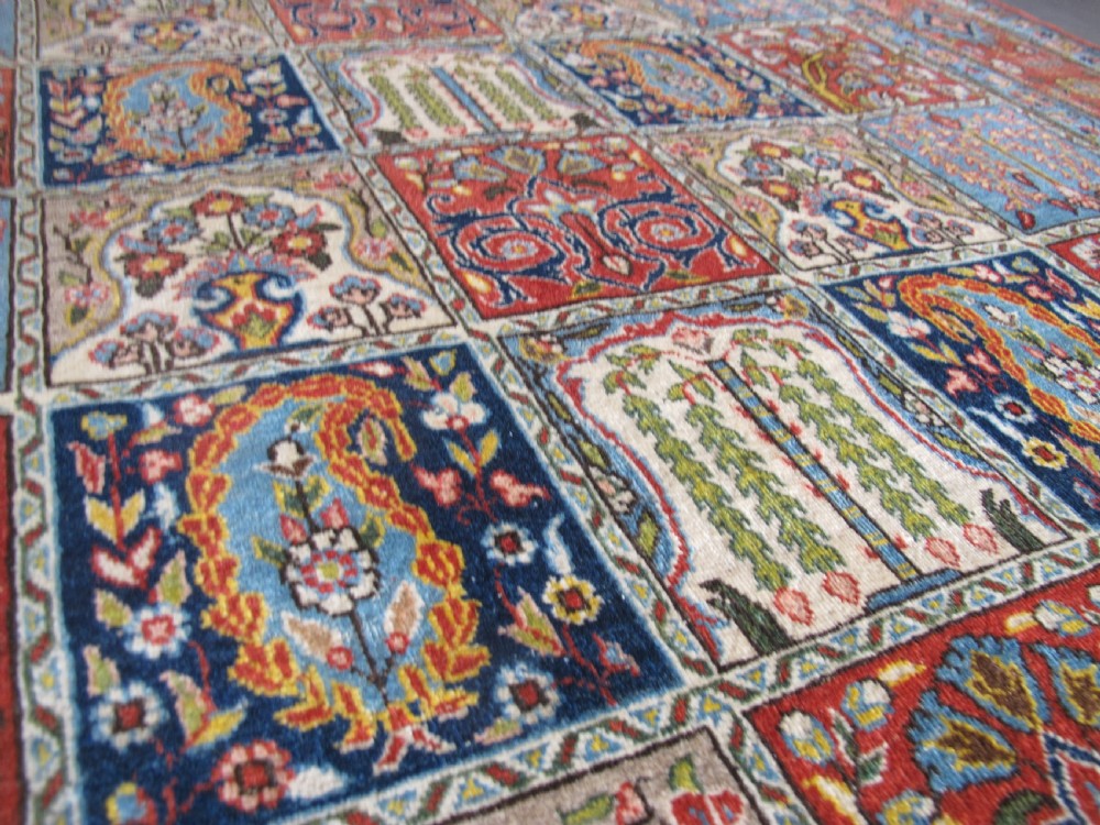 A rectangular hand-knotted Persian Qum rug featuring a central field of grid compartments filled with botanical and cypress motifs framed by a red border. View XIV