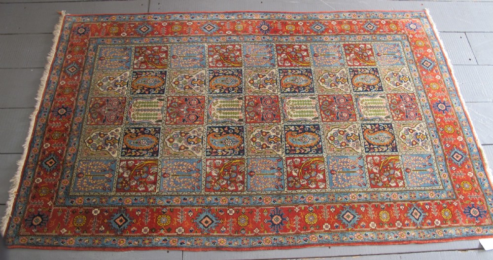 A rectangular hand-knotted Persian Qum rug featuring a central field of grid compartments filled with botanical and cypress motifs framed by a red border. View XV