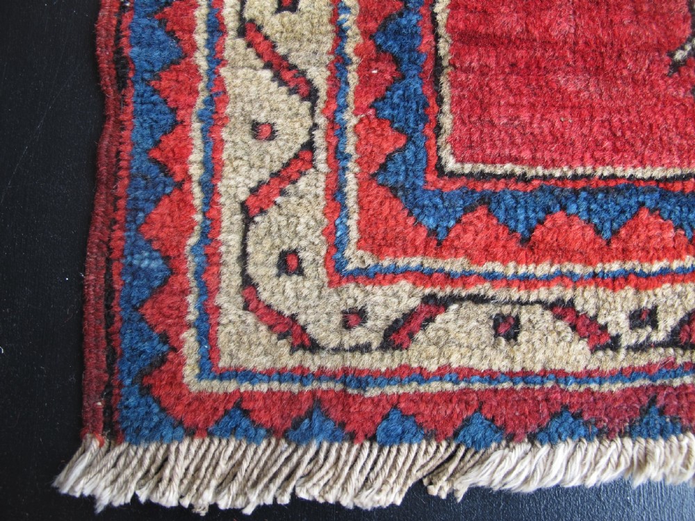 A small hand-knotted North-West Persian wool rug with a central gold diamond medallion surrounded by geometric floral motifs on a vibrant red field with multi-coloured borders. View II