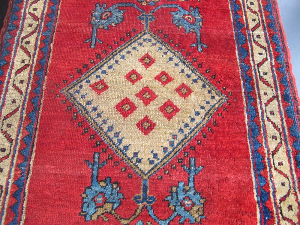 A small hand-knotted North-West Persian wool rug with a central gold diamond medallion surrounded by geometric floral motifs on a vibrant red field with multi-coloured borders. View V