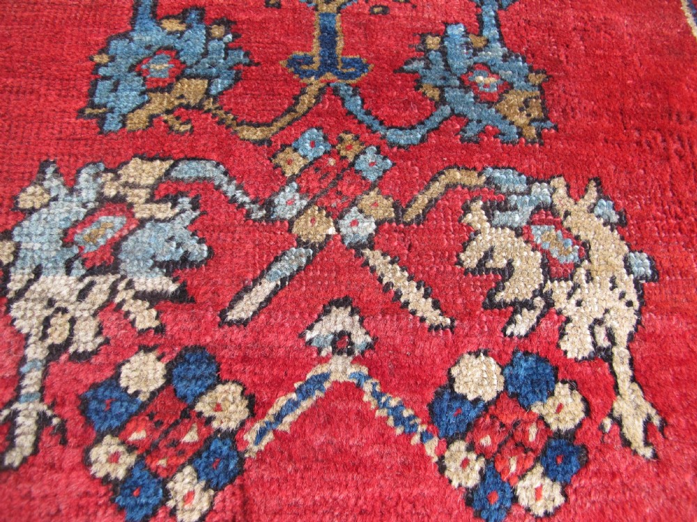 A small hand-knotted North-West Persian wool rug with a central gold diamond medallion surrounded by geometric floral motifs on a vibrant red field with multi-coloured borders. View VI