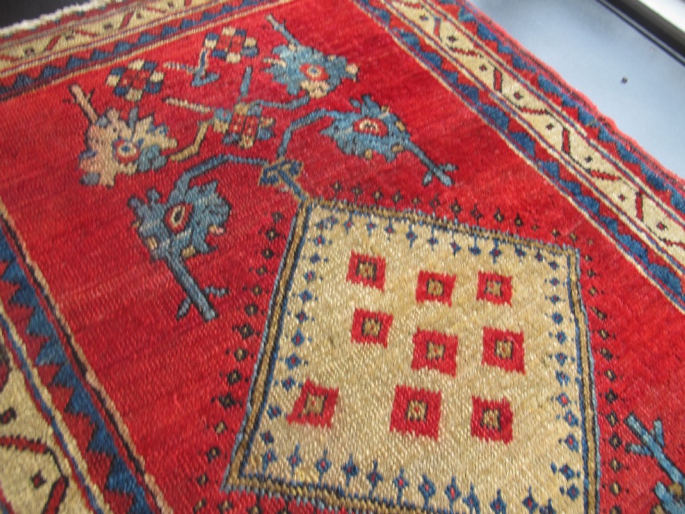 A small hand-knotted North-West Persian wool rug with a central gold diamond medallion surrounded by geometric floral motifs on a vibrant red field with multi-coloured borders. View VII