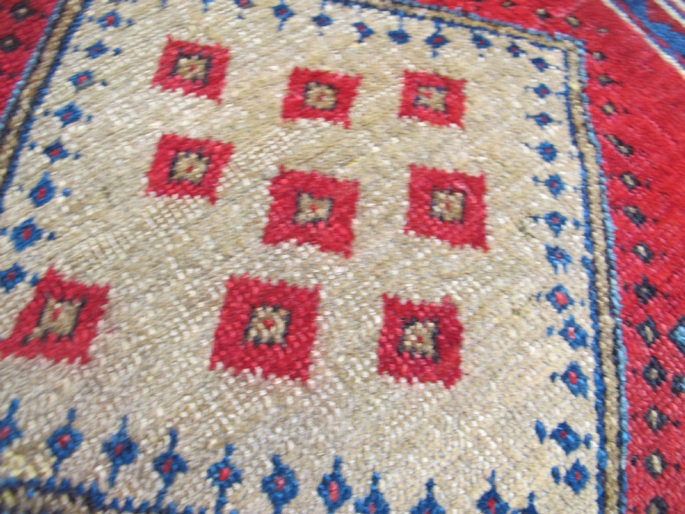 A small hand-knotted North-West Persian wool rug with a central gold diamond medallion surrounded by geometric floral motifs on a vibrant red field with multi-coloured borders. View IX