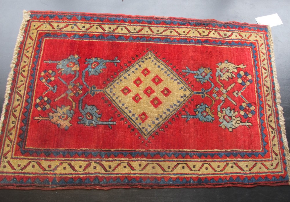 A small hand-knotted North-West Persian wool rug with a central gold diamond medallion surrounded by geometric floral motifs on a vibrant red field with multi-coloured borders. View XIII