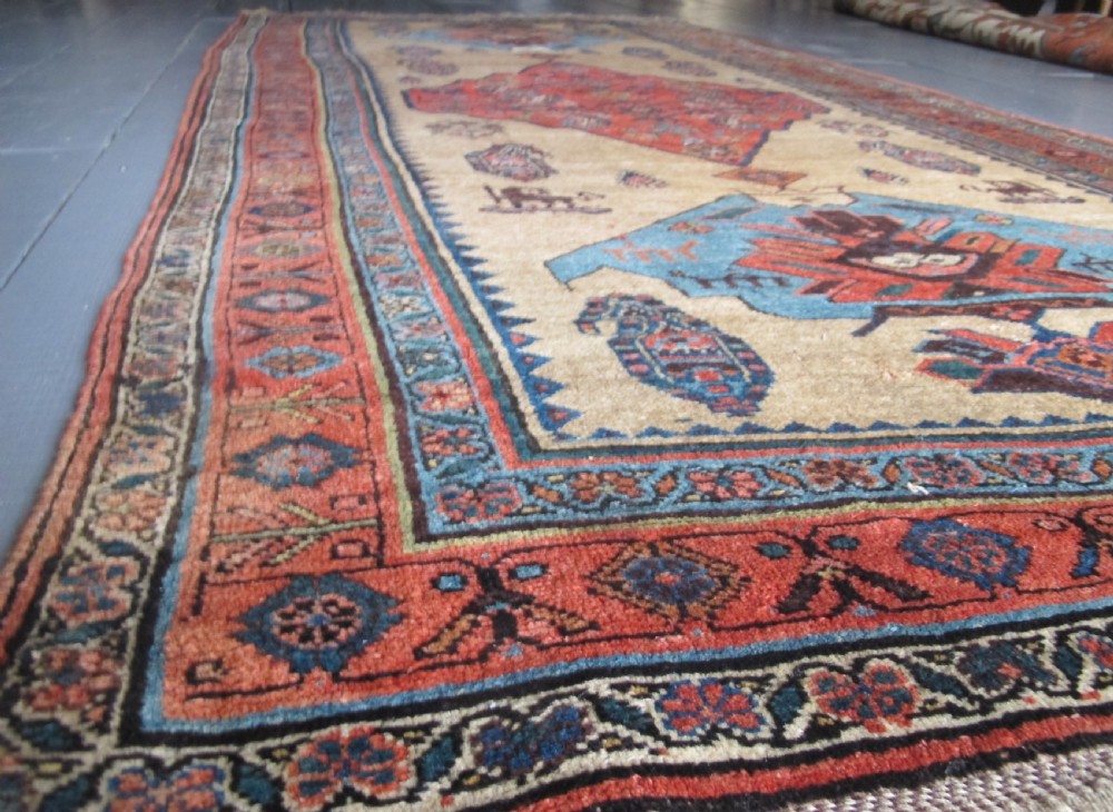 An antique hand-knotted wool long rug featuring a central red diamond medallion on a camel field framed by blue spandrels and multi-banded borders. View III