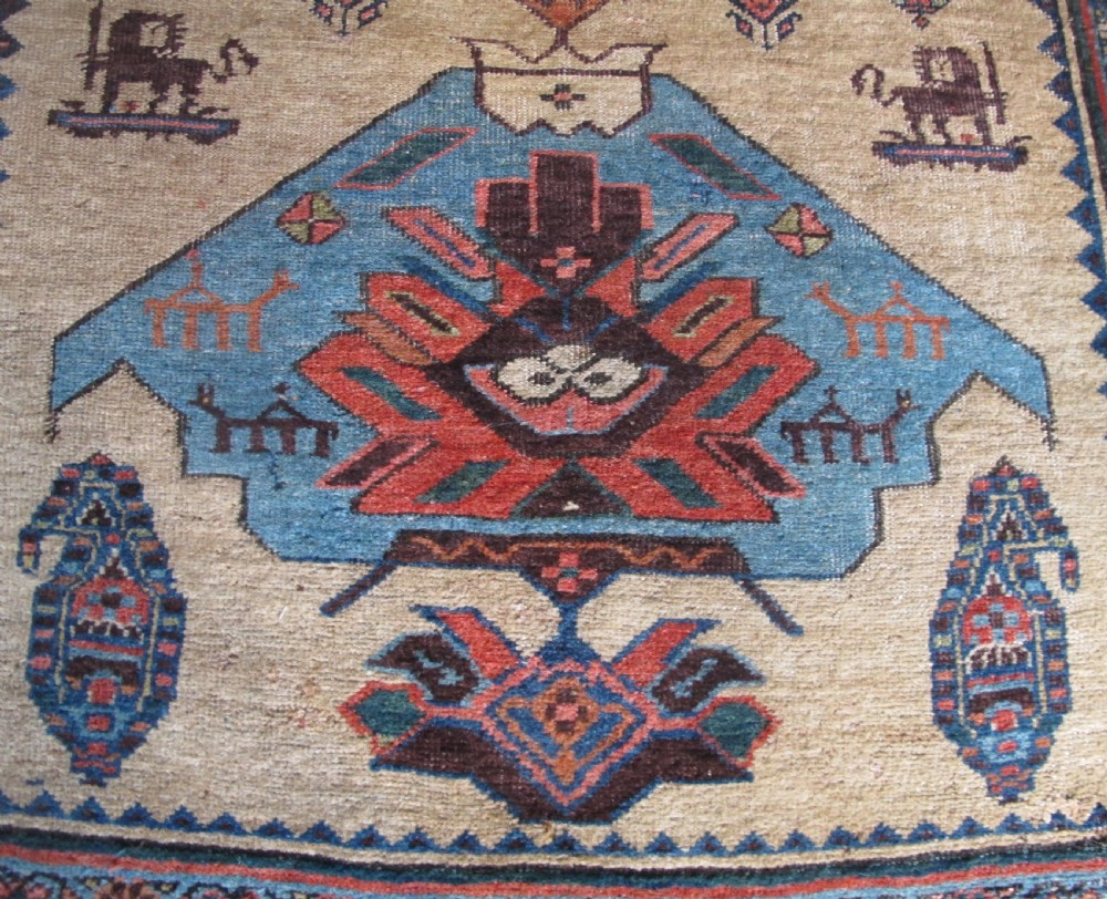 An antique hand-knotted wool long rug featuring a central red diamond medallion on a camel field framed by blue spandrels and multi-banded borders. View IV