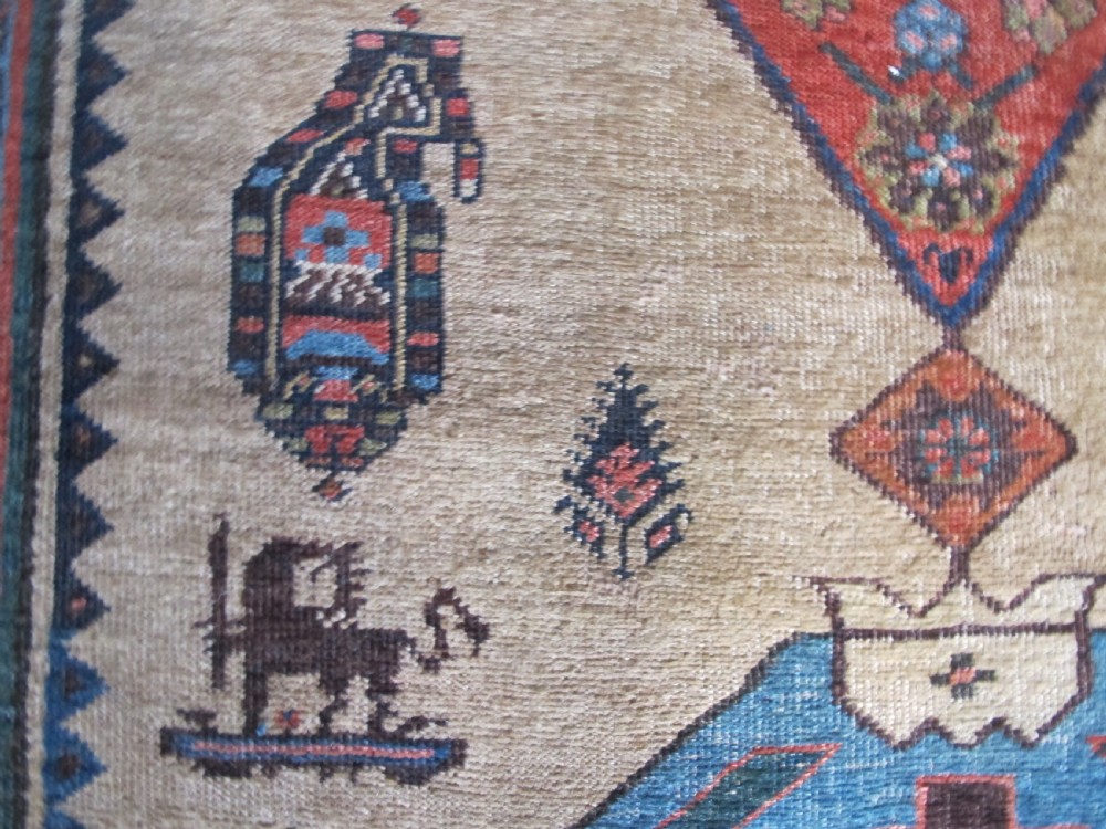 An antique hand-knotted wool long rug featuring a central red diamond medallion on a camel field framed by blue spandrels and multi-banded borders. View V