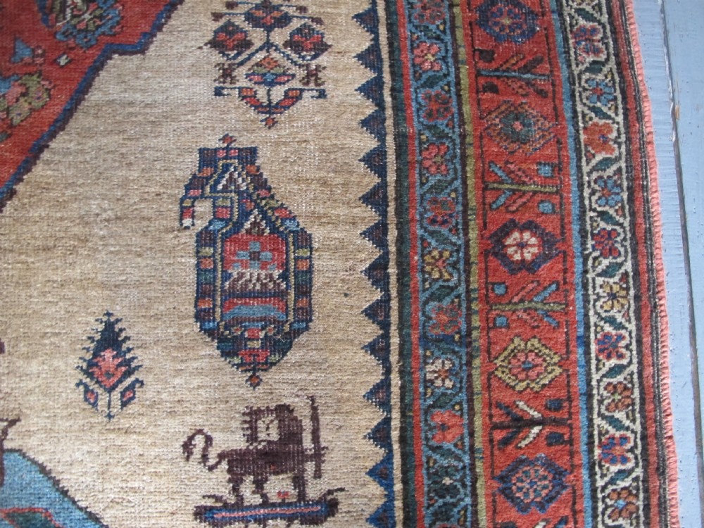 An antique hand-knotted wool long rug featuring a central red diamond medallion on a camel field framed by blue spandrels and multi-banded borders. View VII