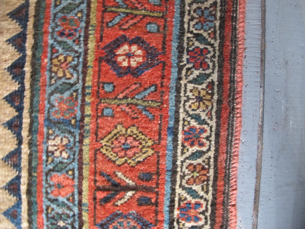 An antique hand-knotted wool long rug featuring a central red diamond medallion on a camel field framed by blue spandrels and multi-banded borders. View VIII