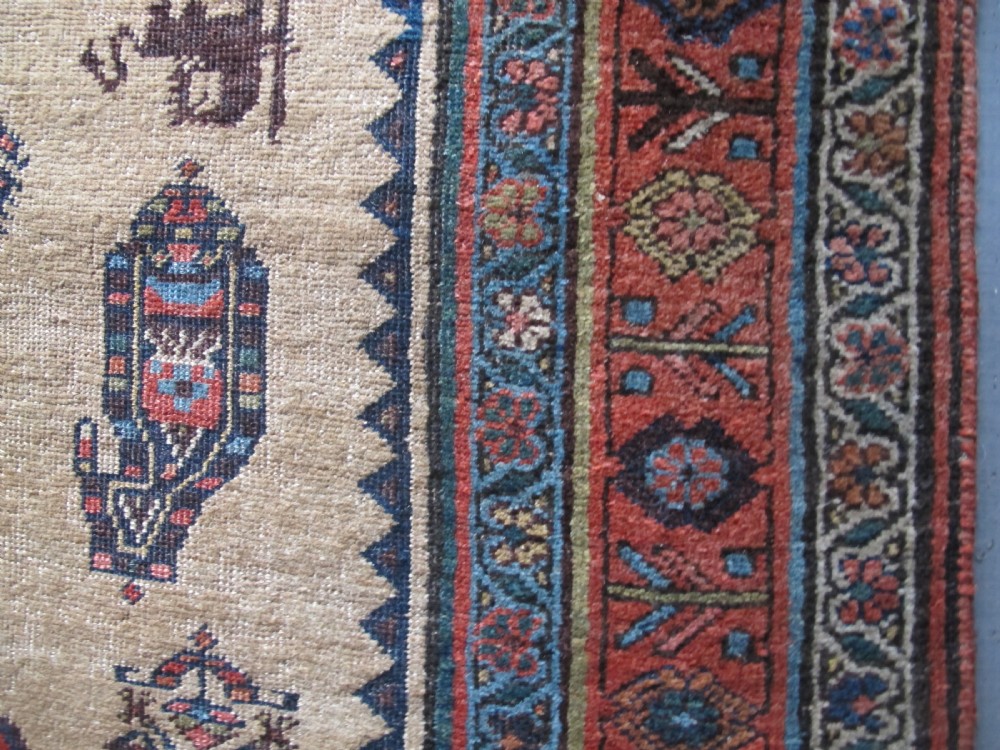 An antique hand-knotted wool long rug featuring a central red diamond medallion on a camel field framed by blue spandrels and multi-banded borders. View IX