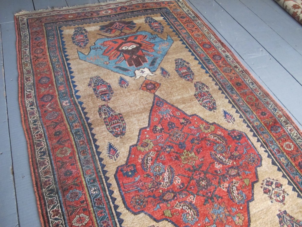 An antique hand-knotted wool long rug featuring a central red diamond medallion on a camel field framed by blue spandrels and multi-banded borders. View X