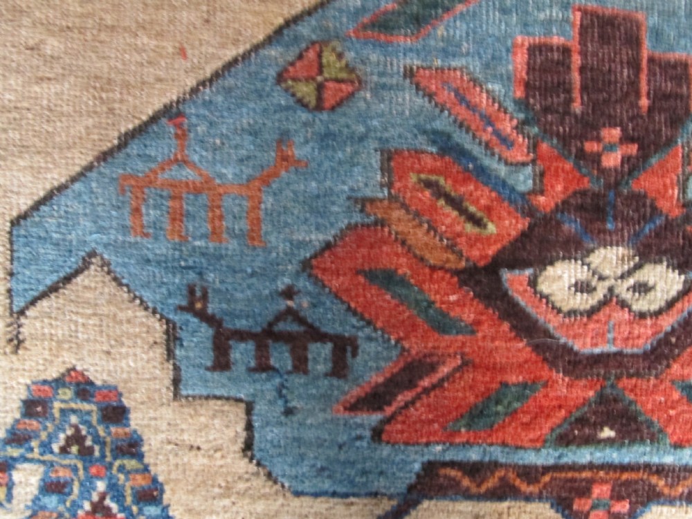 An antique hand-knotted wool long rug featuring a central red diamond medallion on a camel field framed by blue spandrels and multi-banded borders. View XI