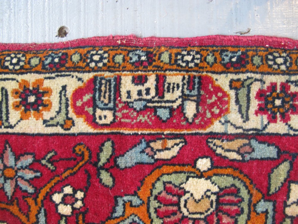 An antique Persian Isfahan hand-knotted wool rug featuring a light blue field with a vase and floral tree motif flanked by deer, framed by a red floral border. View V