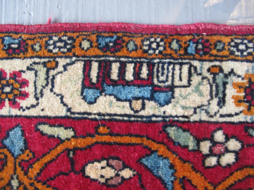 An antique Persian Isfahan hand-knotted wool rug featuring a light blue field with a vase and floral tree motif flanked by deer, framed by a red floral border. View VI