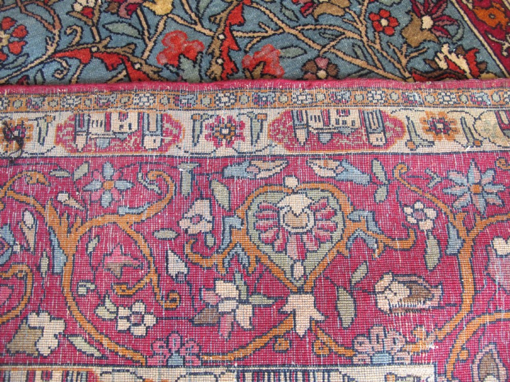 An antique Persian Isfahan hand-knotted wool rug featuring a light blue field with a vase and floral tree motif flanked by deer, framed by a red floral border. View VII
