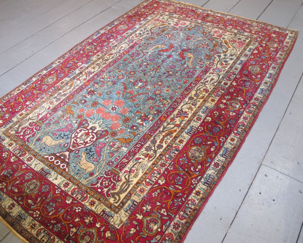 An antique Persian Isfahan hand-knotted wool rug featuring a light blue field with a vase and floral tree motif flanked by deer, framed by a red floral border. View VIII