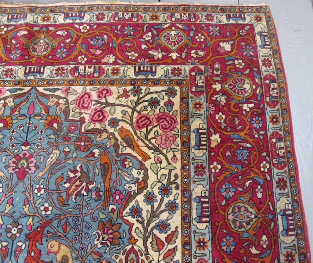 An antique Persian Isfahan hand-knotted wool rug featuring a light blue field with a vase and floral tree motif flanked by deer, framed by a red floral border. View IX