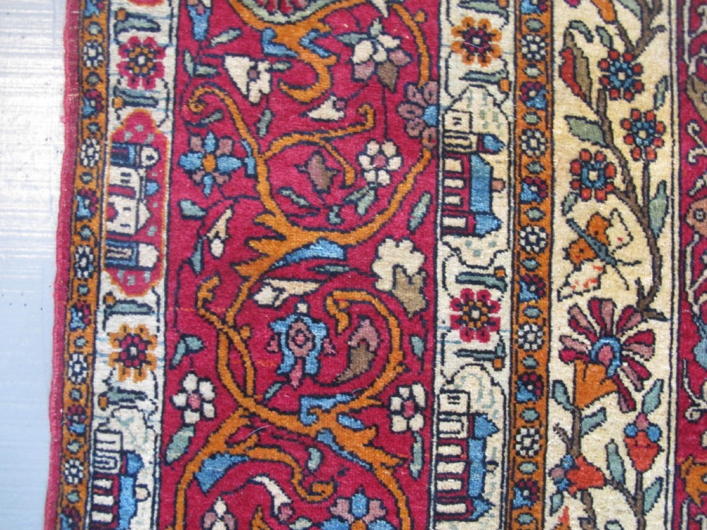 An antique Persian Isfahan hand-knotted wool rug featuring a light blue field with a vase and floral tree motif flanked by deer, framed by a red floral border. View XI