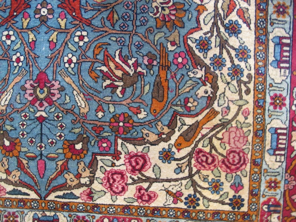 An antique Persian Isfahan hand-knotted wool rug featuring a light blue field with a vase and floral tree motif flanked by deer, framed by a red floral border. View XII