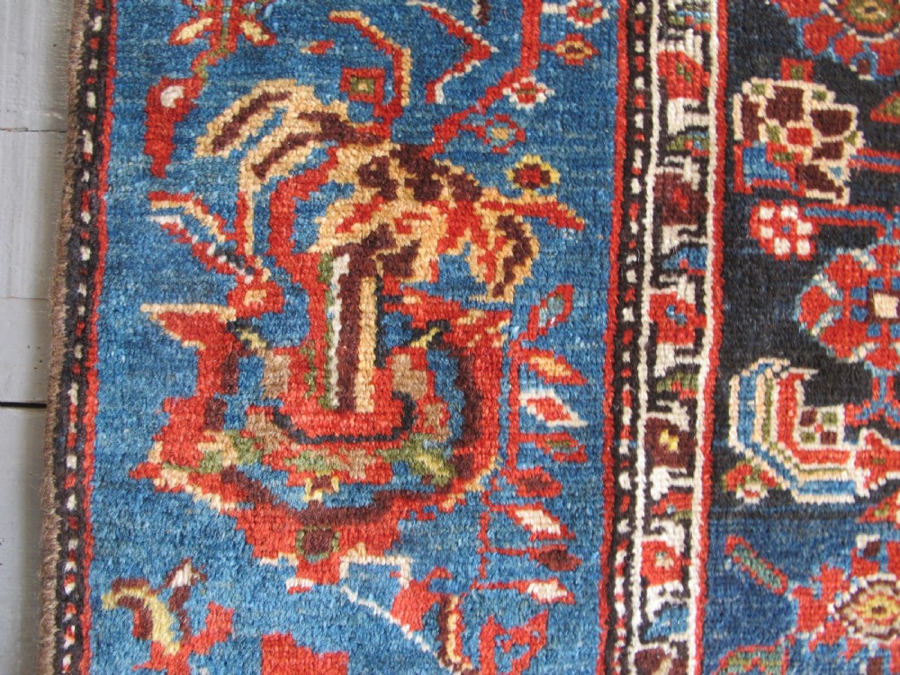 A late 19th-century hand-knotted Persian Hamadan wool rug featuring a dark navy central field surrounded by vibrant blue and red borders with intricate geometric floral motifs. View VI