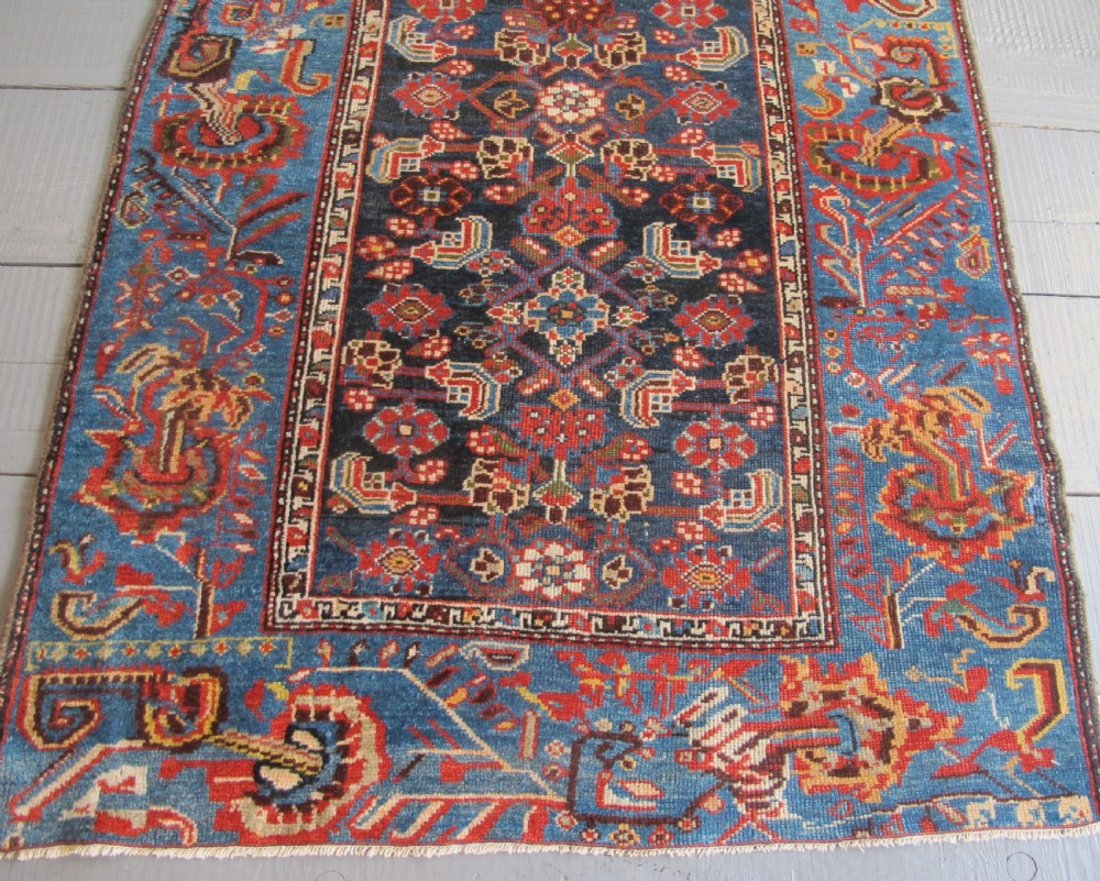 A late 19th-century hand-knotted Persian Hamadan wool rug featuring a dark navy central field surrounded by vibrant blue and red borders with intricate geometric floral motifs. View XII