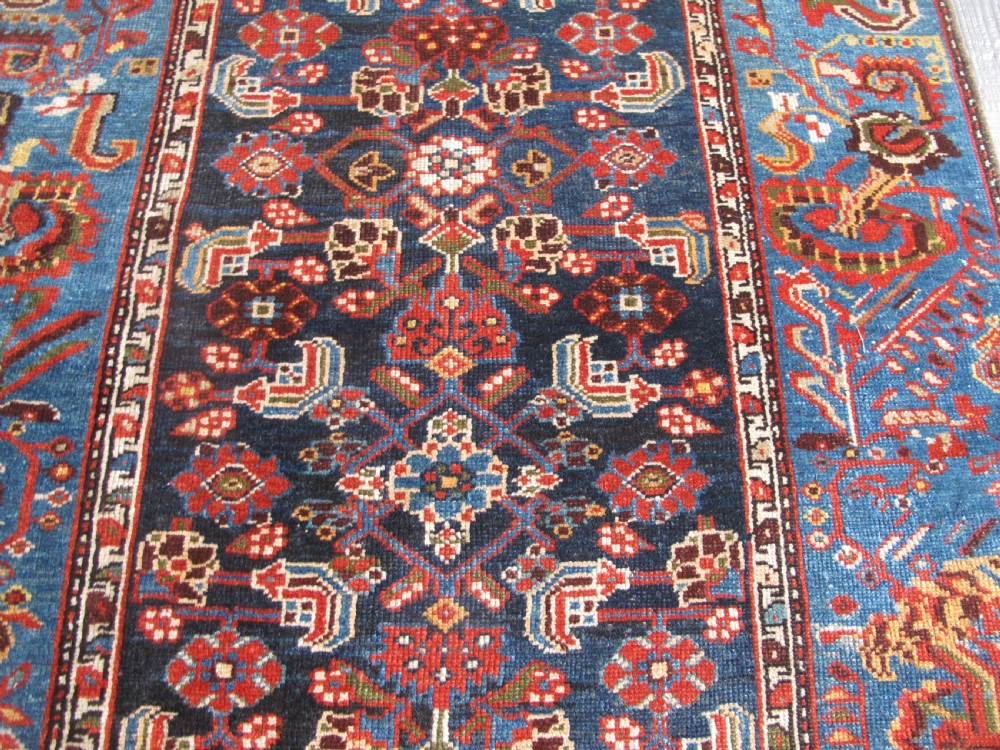 A late 19th-century hand-knotted Persian Hamadan wool rug featuring a dark navy central field surrounded by vibrant blue and red borders with intricate geometric floral motifs. View XVIII